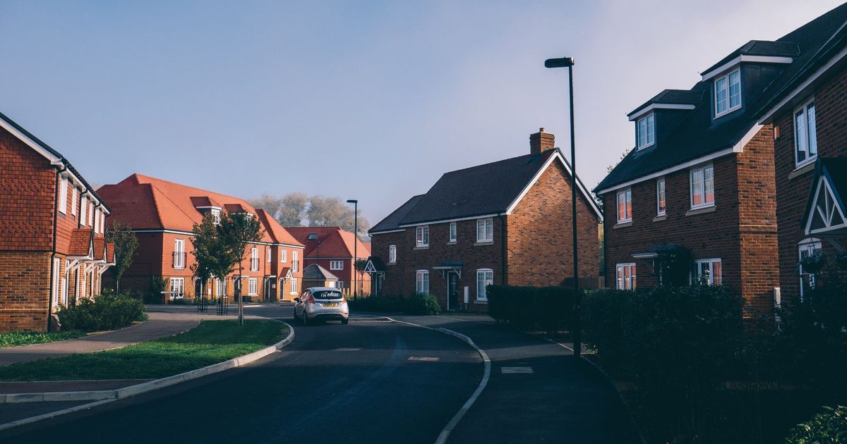 A quiet English suburban street lined with traditional red-brick terraced houses.