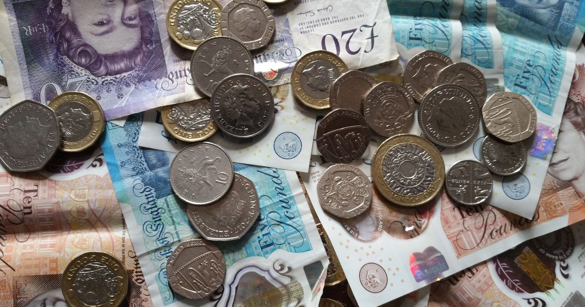 British coins resting on paper banknotes, showing a mix of UK currency denominations.